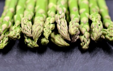 Green asparagus on a black slate. Selective focus. Front view.
