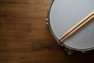 Drum stick and drum on wooden table background, music instrument concept