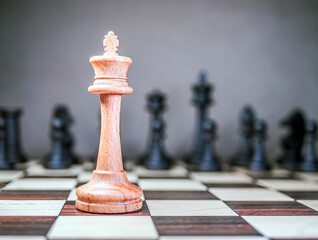 Lone chess king is standing in front of the formation of the opponent's pieces. Selective focus....