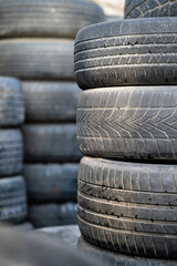 Closeup of old used rubber tires stacked with high piles. Tyre dump. Hazardous waste requiring...