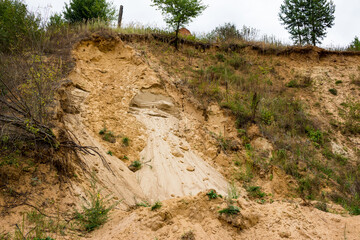 Creeping fine-grained sand on the slope of a sand pit, artisanal mining of building material