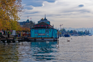 Lake Z&uuml;rich seen from City of Z&uuml;rich with floating blue ship theatre and beautiful autumn trees on a blue cloudy autumn day. Photo taken October 30th, 2022, Zurich, Switzerland.