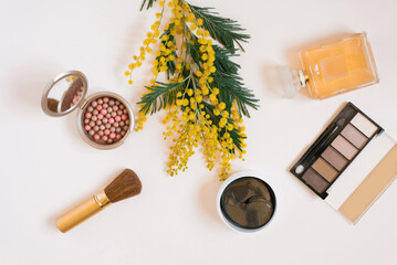 Flat lay fashion blogger. Decorative cosmetics and perfume and a branch of yellow mimosa flowers on a white background