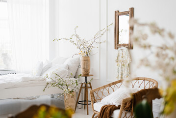 A vase with beautiful white flowering branches on the bedside table in the bedroom