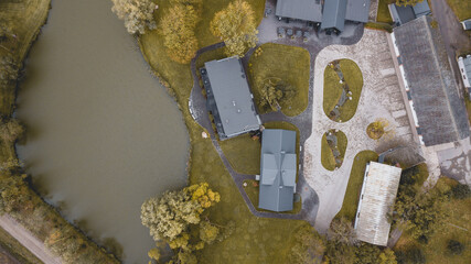 Aerial drone photo of autumnal scene with houses with grey roofs and pond next to the complex