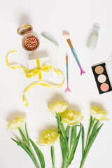 Decorative flat lay composition with cosmetics and flowers. Flat lay, top view on white background