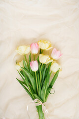 A bouquet of spring flowers of tulips on a beige fabric background. Flat lay for wedding day, Easter and Valentine's day and birthday