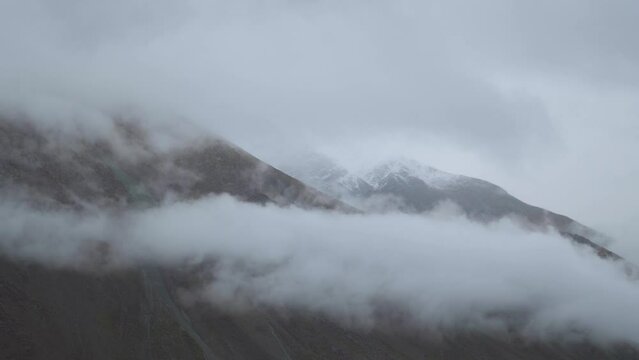 4K shot of fog around the mountain peaks during the stormy weather at Tandi in Lahaul Spiti district at Himachal Pradesh, India. Clouds rolling over the peaks of the mountain. Nature background. 