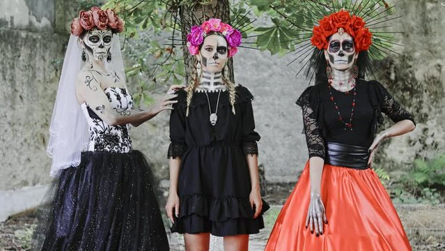 Slow motion Costume performance group portrait of three Women in the guise of Holy Death against the background of the ruins. Traditional Dia de Los Muertos Festival in Mexico