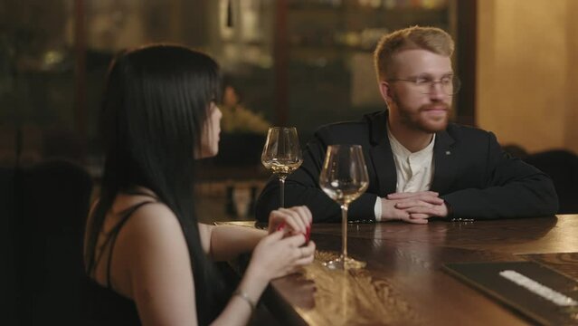 pretty young woman and her friend drink wine in bar of hotel in evening, nice talk with stranger