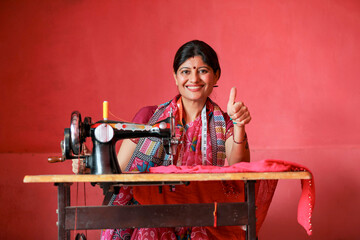 Indian rural woman using sewing machine and showing thumps up