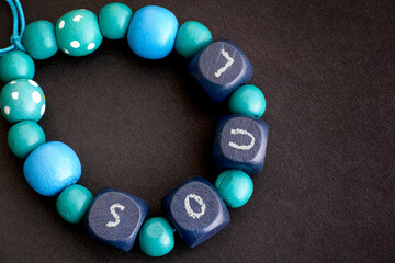 Bracelet of blue wooden beads with letters SOUL on a black background