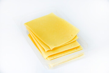 Thinly sliced slices of cheese on a plastic backing. Delicious chopped yellow cheese. Cheese in a package from the store.