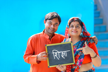 Indian rural couple showing slate. Shiksha word in marathi calligraphy on slate