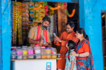 Indian rural customer using smartphone for digital payment at groceries shop