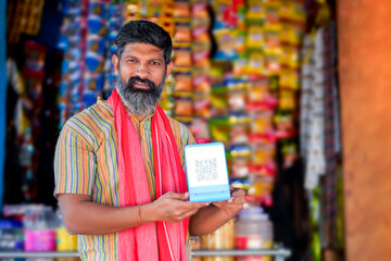 Digital payment concept : Indian shopkeeper showing qr scanner at his shop
