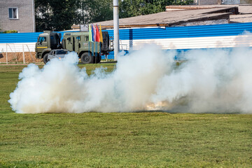 Fototapeta premium A white smoke bomb on green grass in summer.