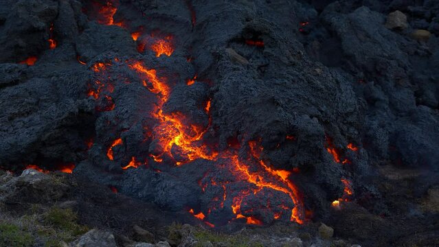 Close up camera view of cooling lava. Hot red magma becoming stone. Fumes around fresh lava.