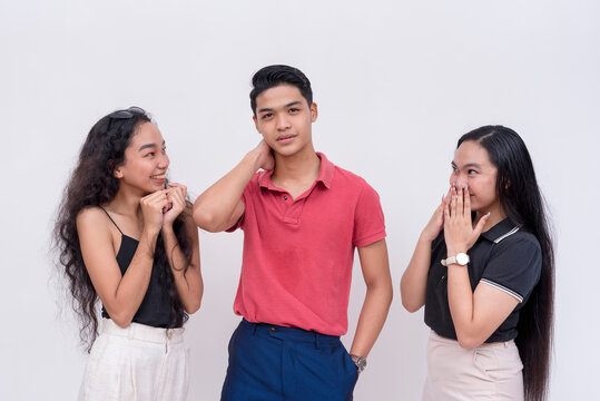 A Popular Young Man Feeling Handsome And Full Of Himself After Getting The Attention Of Two Enamored Women. Isolated On A White Background.