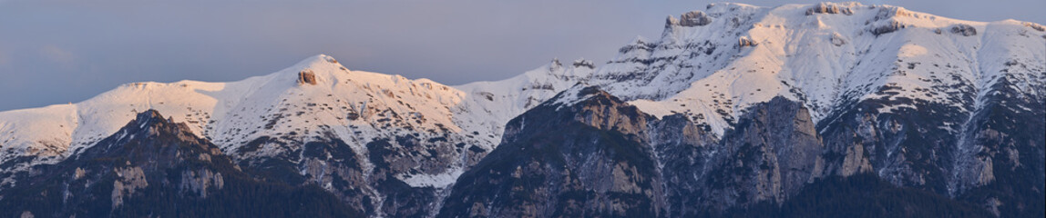 Panoramic view of mountain ridge covered by snow at sunset