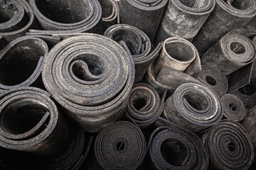 Old sheet rubber of black color, twisted into rolls, top view. rubber waste.