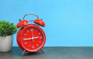 Red vintage alarm clock on wooden table on white background
