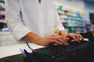 Fototapeta na wymiar Pharmacist woman works at computer at the pharmacy counter