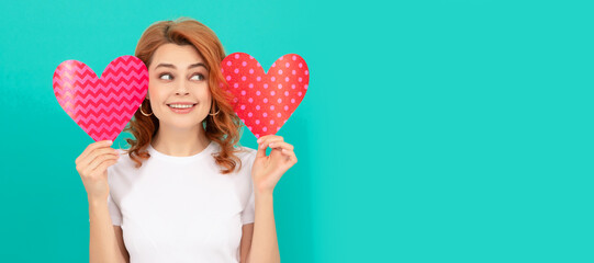 positive young lady with red heart on blue background. Woman isolated face portrait, banner with mock up copyspace.