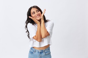 Woman in white t-shirt on white background brunette hands up gestures and signals poses in jeans emotion, lifestyle smiles, copy space
