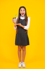 Amazed teen girl. Teenage girl with take away cup of cappuccino coffee or tea. Child with takeaway cup on yellow background, morning drink beverage. Excited expression, cheerful and glad.