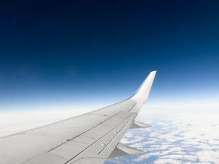 Obraz premium White wing from airplane window on sunny day. Great views of landscape. Aerial view of clouds through a plane window. Wing of airplane with blue sky and beauty clouds