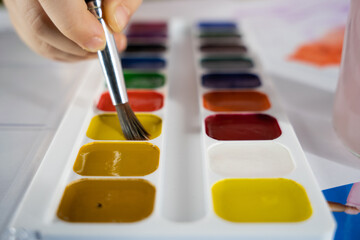 the child draws with a brush and watercolor