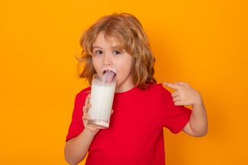 Cute little child with glass of milk on studio color background. Kid with milk moustache. Fun...