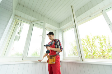 Construction worker repairing plastic window with screwdriver indoors, closeup.