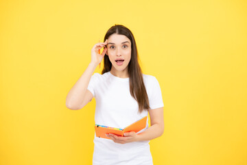 Portrait of student woman. College or high school ducation. Serious young woman with notebooks at camera on yellow studio background. Young female university student.