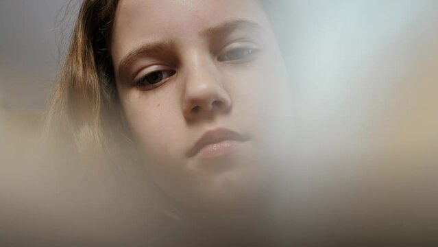 A close-up of a teenage girl who opens a book, reads it and flips through the pages. The girl carefully studies the book and closes it.