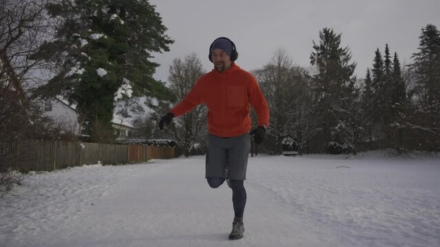 Male jogger running on a slippery snow surface in a park in winter in loose footwear in winter. Wrong sneakers for running in snowy weather. Workout safety. Training outside in cold snowy weather. 