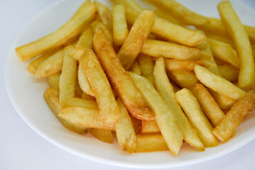 Yellow delicious French fries in white dishes. Fast food on a plate. Fried potatoes. Toasted potato slices on a white background.