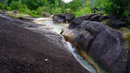 Natural landscape with black rock formations, which are fed by a tributary