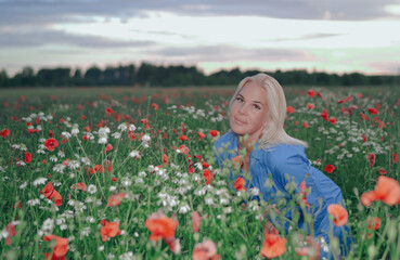 Beautiful girl on the field with poppies at sunset.