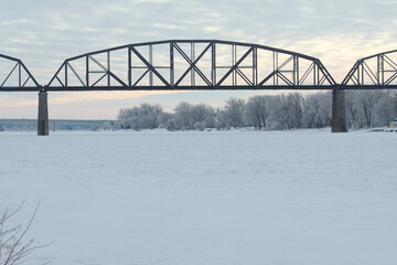 A train bridge crosses over a frozen river
