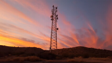 A communications tower with colorful sunset clouds - Powered by Adobe