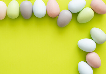 Colorful quail eggs on a light yellow background - an Easter composition. Background for greeting cards, invitations, greetings.