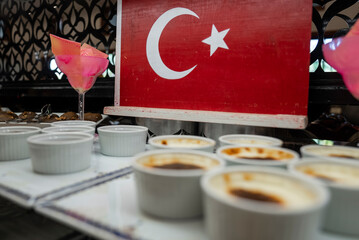 Close-up of bowls with rice pudding served on table in front of Turkish national flag at buffet in...