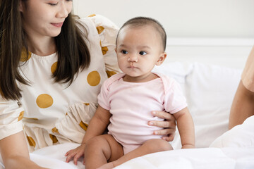 Toddlers are feeling safe and happy with their parents' care in bed at home. Asian family takes care of their children's health with love. Young children are learning to develop their brains.