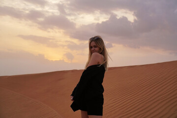 Young woman in the desert. She is wearing a black sweater and shorts