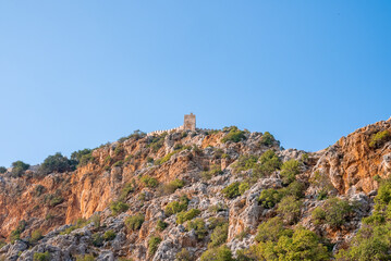 Fototapeta na wymiar Side, Turkey. October 10, 2022. Low angle distant view of medieval Alanya Castle on top of majestic rocky mountain with clear blue sky in the background