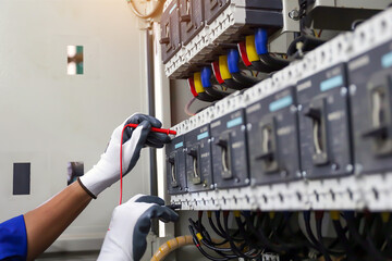 Electricity or electrical maintenance service, Engineer hand checking electric current voltage at circuit breaker terminal and cable wiring check in main power load center distribution board.