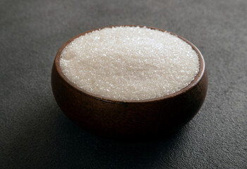 Granulated sugar in bowl on dark background
