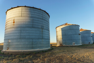 4 silos for grain storage in a field. diminishing perspective